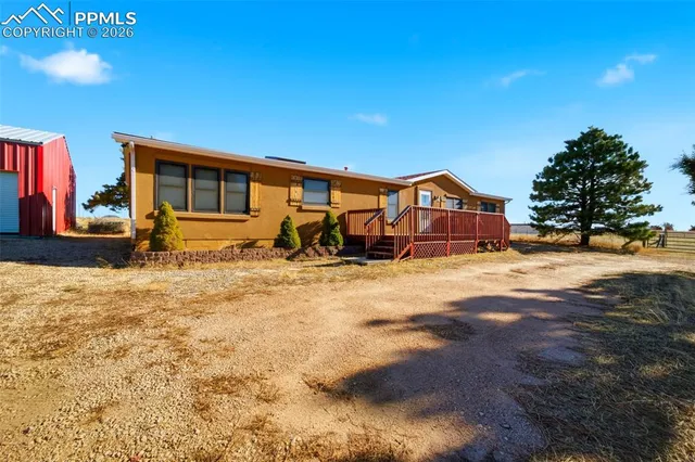 a front view of a house with a yard covered with snow and trees