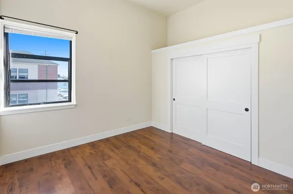a view of an empty room with wooden floor and a window