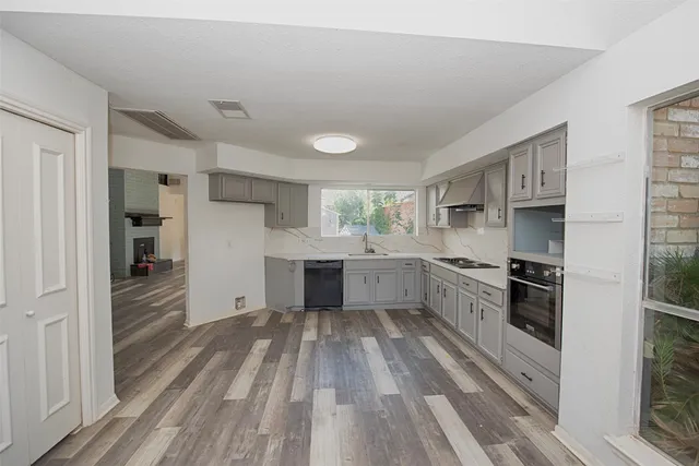 a view of a kitchen with an empty room and wooden floor