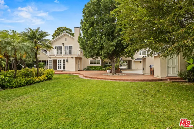 a view of a white house with a big yard and large trees