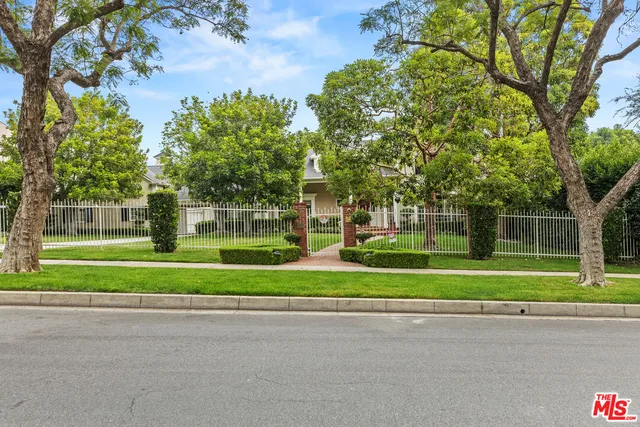 a view of a house in a big yard with large trees
