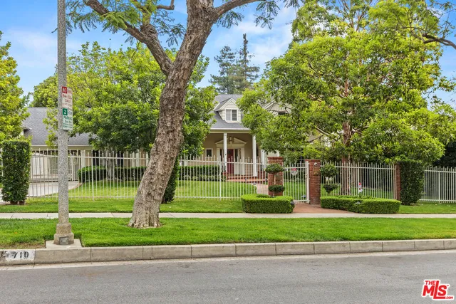 a view of a house with a big yard plants and a large tree