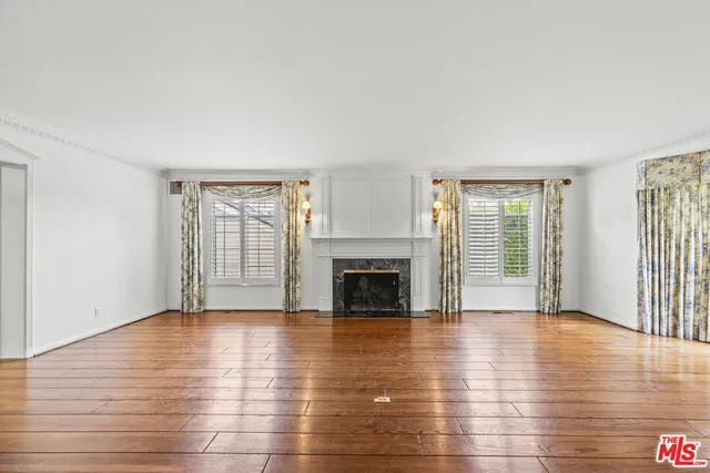 wooden floor fireplace and windows in an empty room