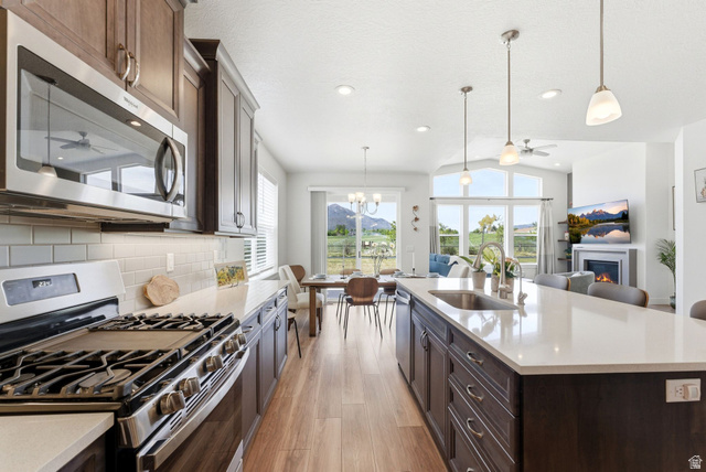 108 West Monte Rosa Lane Midway, UT 84049 - Photo 9 of 48 Gourmet kitchen with stainless steel appliances, white subway tile backsplash, light wood-finish flooring, and a spacious island featuring an undermount sink