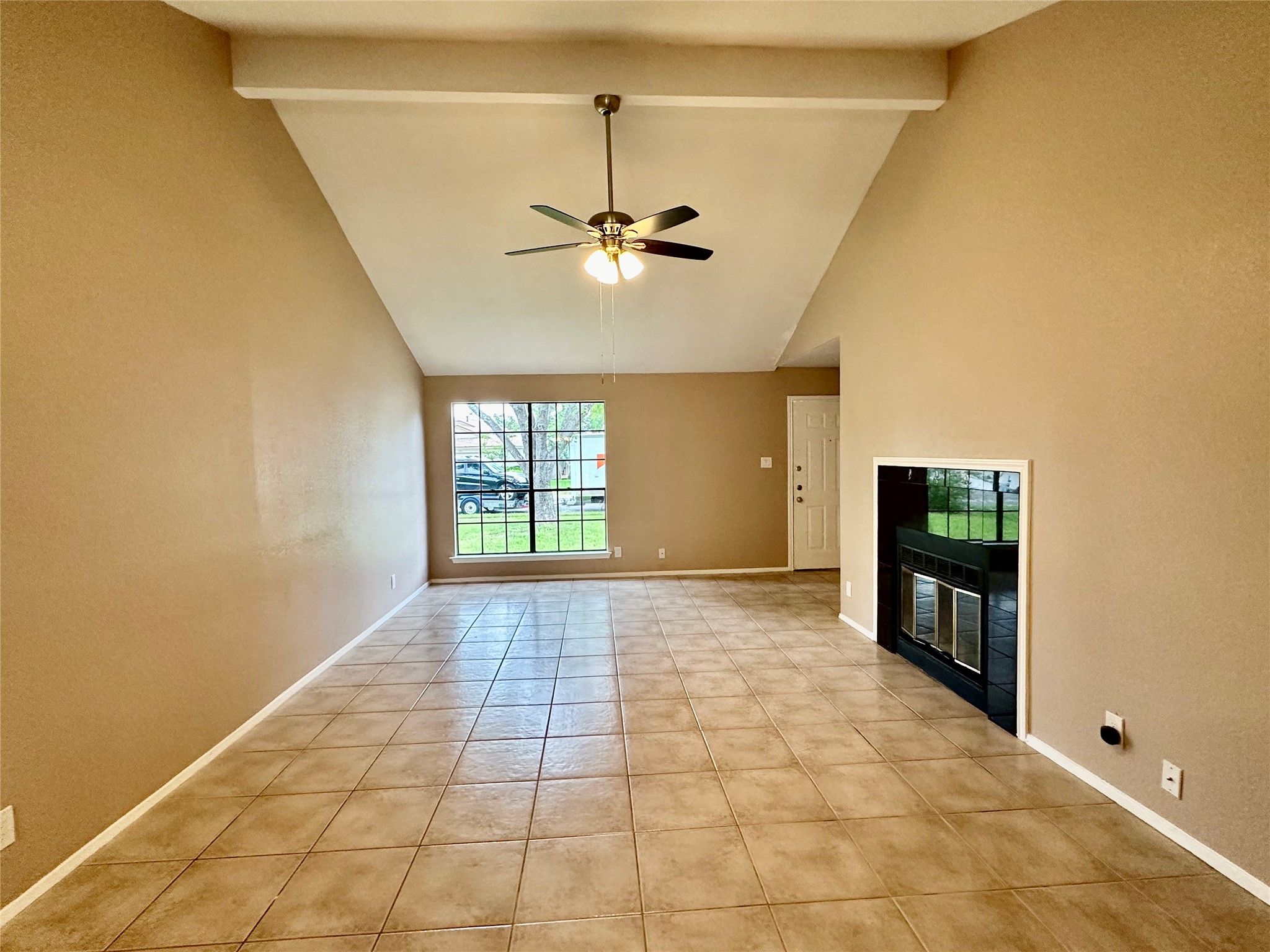 709 Brookside Pass Cedar Park, TX 78613 - Photo 4 of 10 Spacious living area featuring a vaulted ceiling with a fan, tiled flooring, a prominent window, and a built-in fireplace