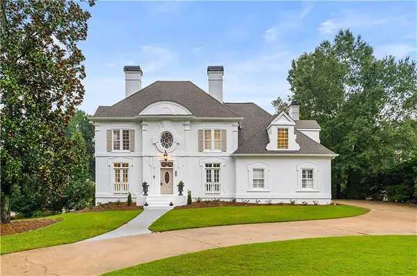 a view of white house with a big yard and large trees
