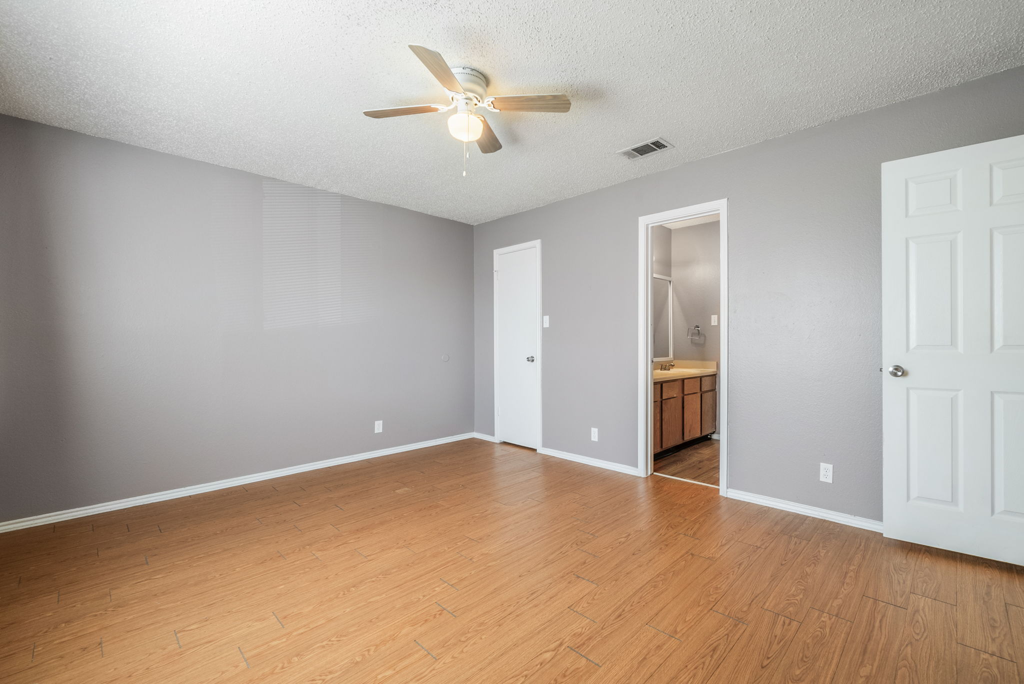 5807 Spring Meadow Road, Unit B Austin, TX 78744 - Photo 18 of 31 A spacious bedroom with rich hardwood-style flooring, a ceiling fan, and access to an adjoining bathroom.
