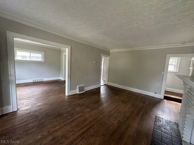 1752 South Taylor Road Cleveland, OH 44118 - Photo 3 of 14 Empty room featuring a textured ceiling, ornamental molding, a fireplace, and dark wood-type flooring