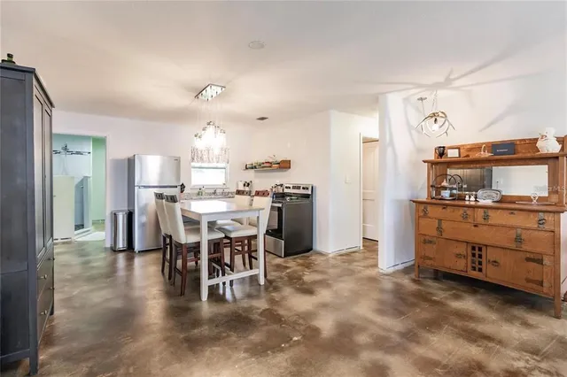 a kitchen with kitchen island a dining table chairs cabinets and stainless steel appliances
