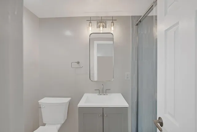 a bathroom with a granite countertop sink a toilet and a mirror