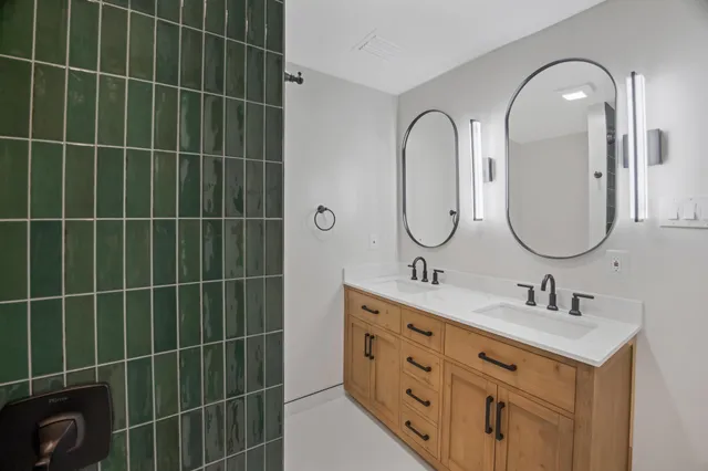 a bathroom with a double vanity sink a toilet a mirror and a shower