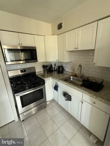 a kitchen with stainless steel appliances a stove a microwave a sink and cabinets