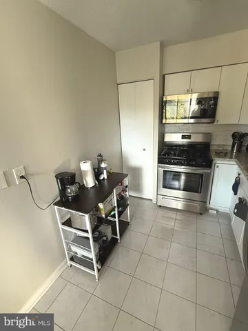 a room with a chair and white cabinets