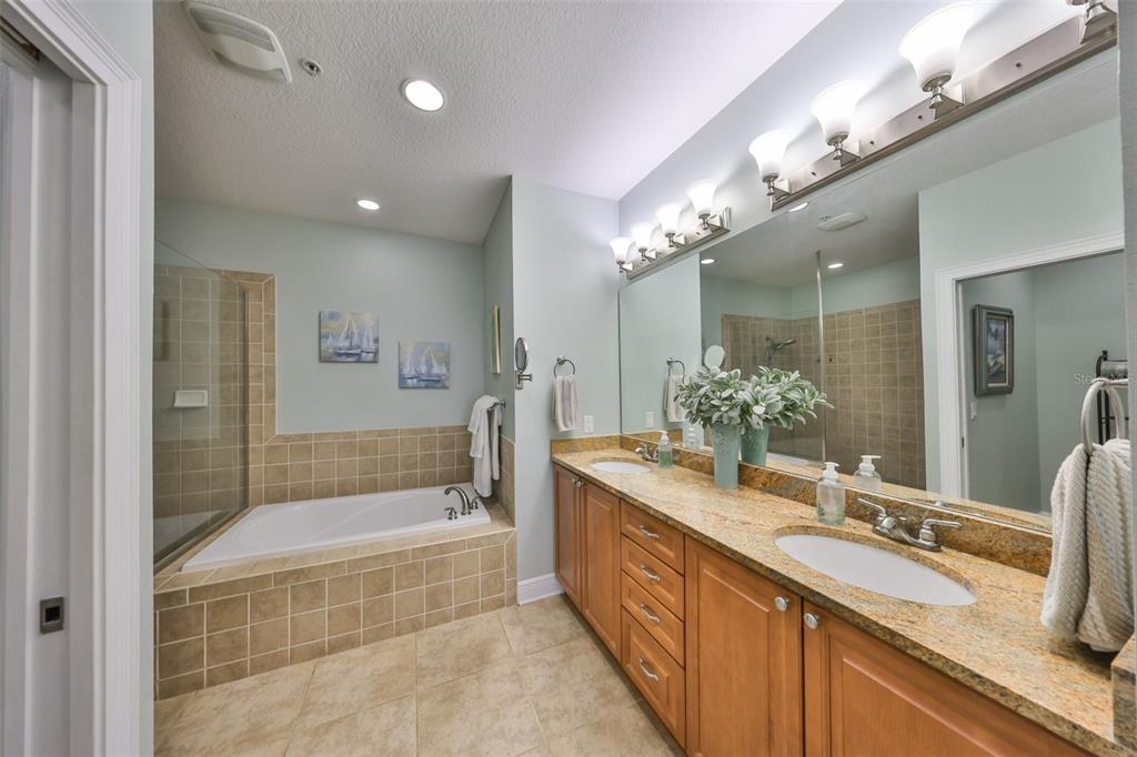 1030 Bellasol Way, Unit 302 Apollo Beach, FL 33572 - Photo 18 of 39 a bathroom with a granite countertop tub a double vanity sink and a large mirror