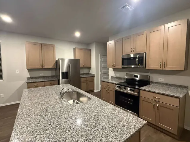 a kitchen with stainless steel appliances granite countertop a stove refrigerator sink and microwave