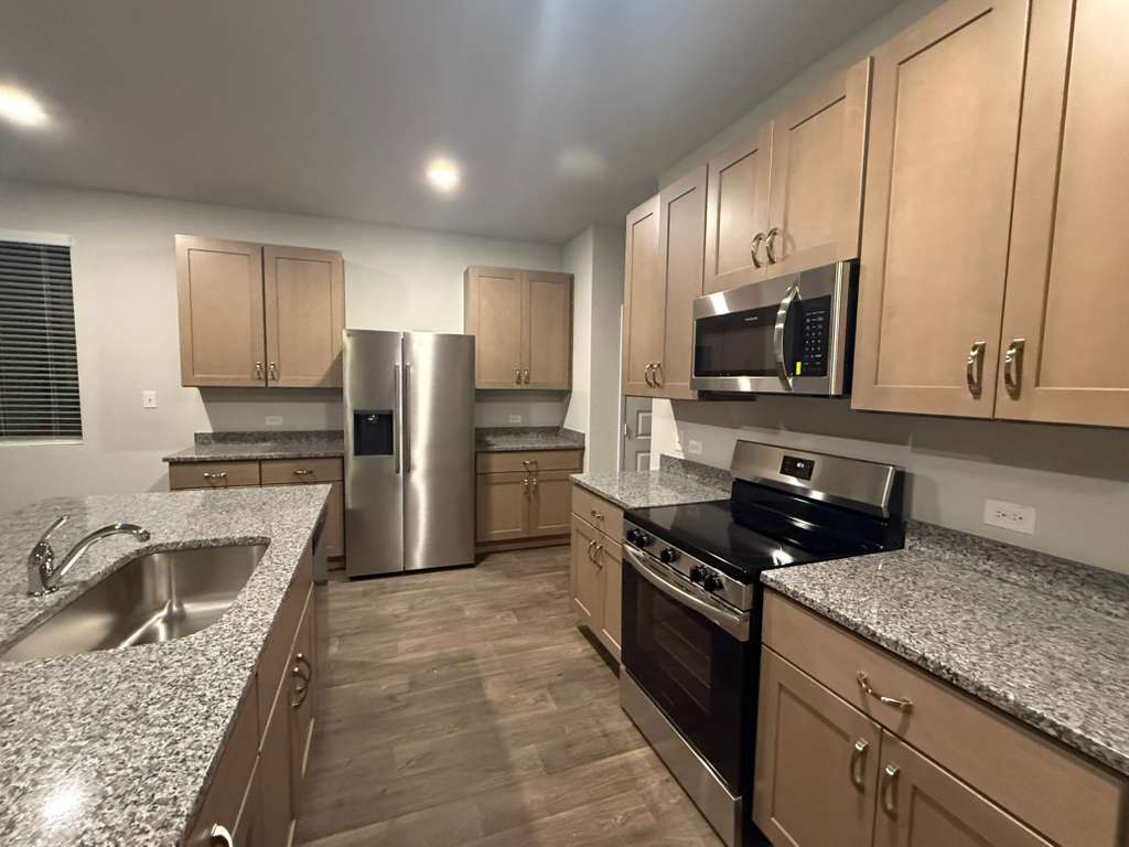 2709 Towy Road Pflugerville, TX 78660 - Photo 8 of 38 Kitchen featuring appliances with stainless steel finishes, dark wood-style flooring, light stone countertops, and recessed lighting