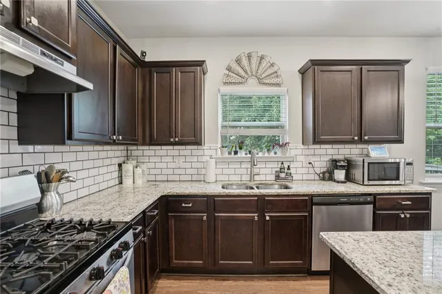 a kitchen with stainless steel appliances granite countertop a sink stove and cabinets