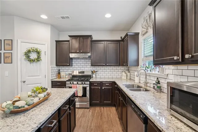 a kitchen with stainless steel appliances granite countertop a sink stove and refrigerator