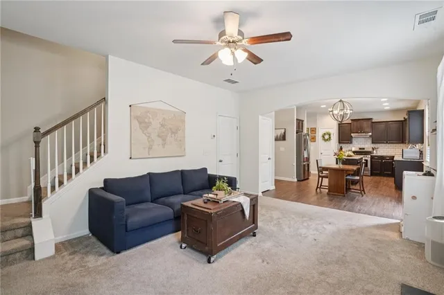 a living room with furniture kitchen view and a chandelier