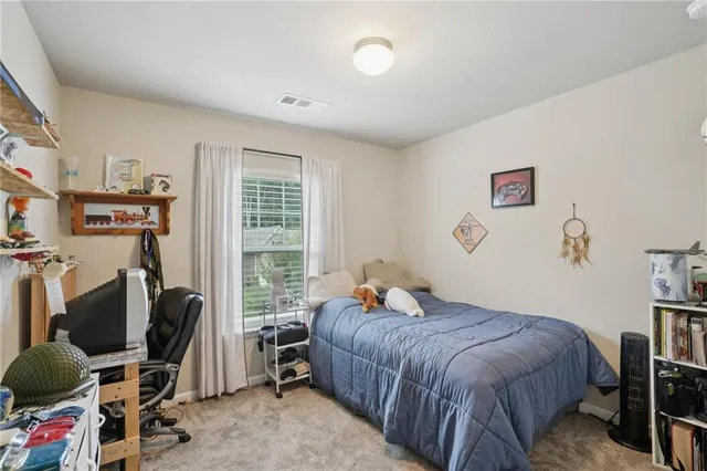 a bedroom with a bed a computer on the desk and a book shelf