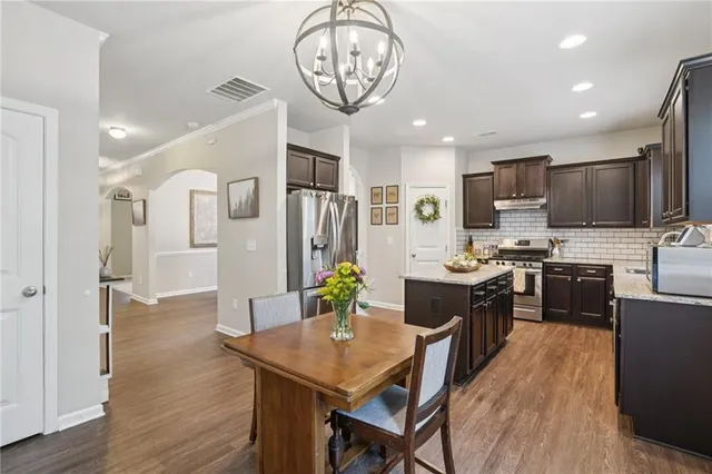 a kitchen with stainless steel appliances granite countertop a refrigerator a stove a microwave a sink a stove and island with wooden floor