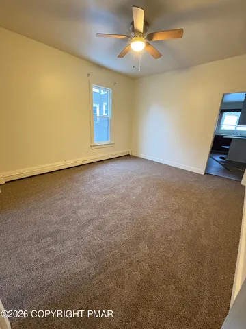 an empty room with windows and chandelier fan