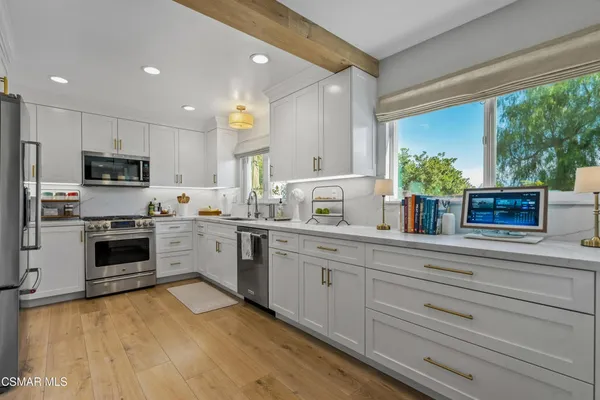 a kitchen with a sink cabinets stainless steel appliances and a large window