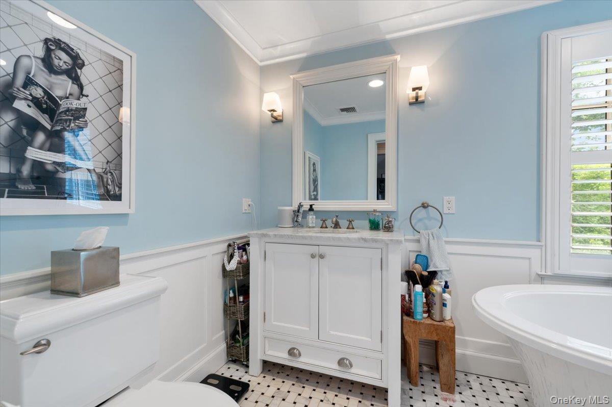 5 Fox Hunt Court Cold Spring Harbor, NY 11724 - Photo 19 of 42 Bathroom featuring a freestanding bathtub, white vanity with stone countertop, wall-mounted sconces, and classic black and white tile flooring