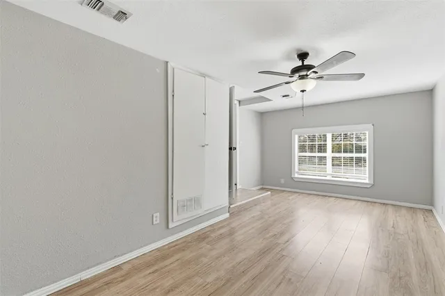 a view of an empty room with a window and wooden floor