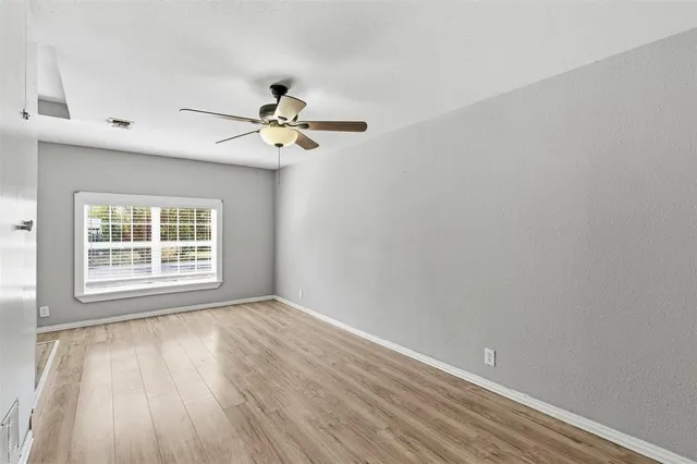 a view of an empty room with a window and a ceiling fan