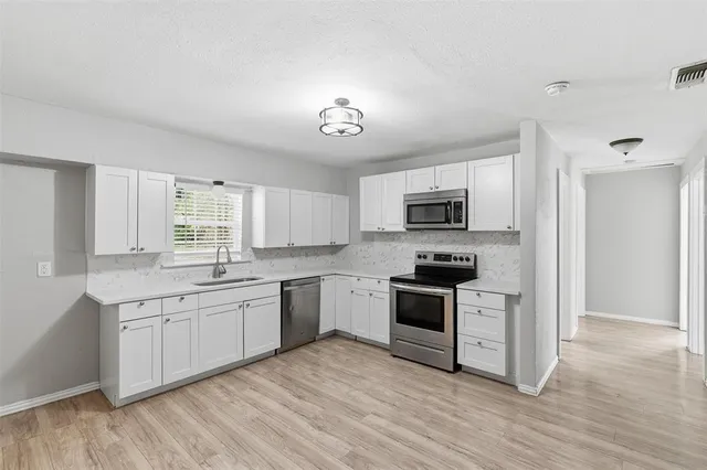 a kitchen with stainless steel appliances granite countertop a stove top oven a sink dishwasher and a refrigerator with wooden floor