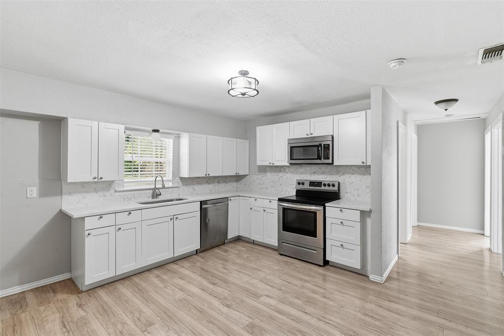 405 North Carr Avenue Sherman, TX 75090 - Photo 2 of 22 a kitchen with stainless steel appliances granite countertop a stove top oven a sink dishwasher and a refrigerator with wooden floor