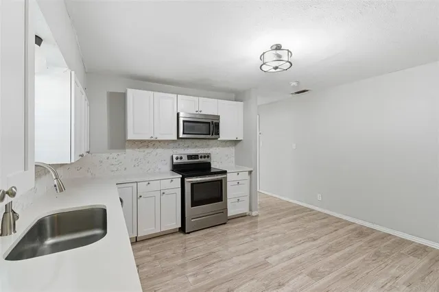 a kitchen with granite countertop a sink stainless steel appliances and white cabinets