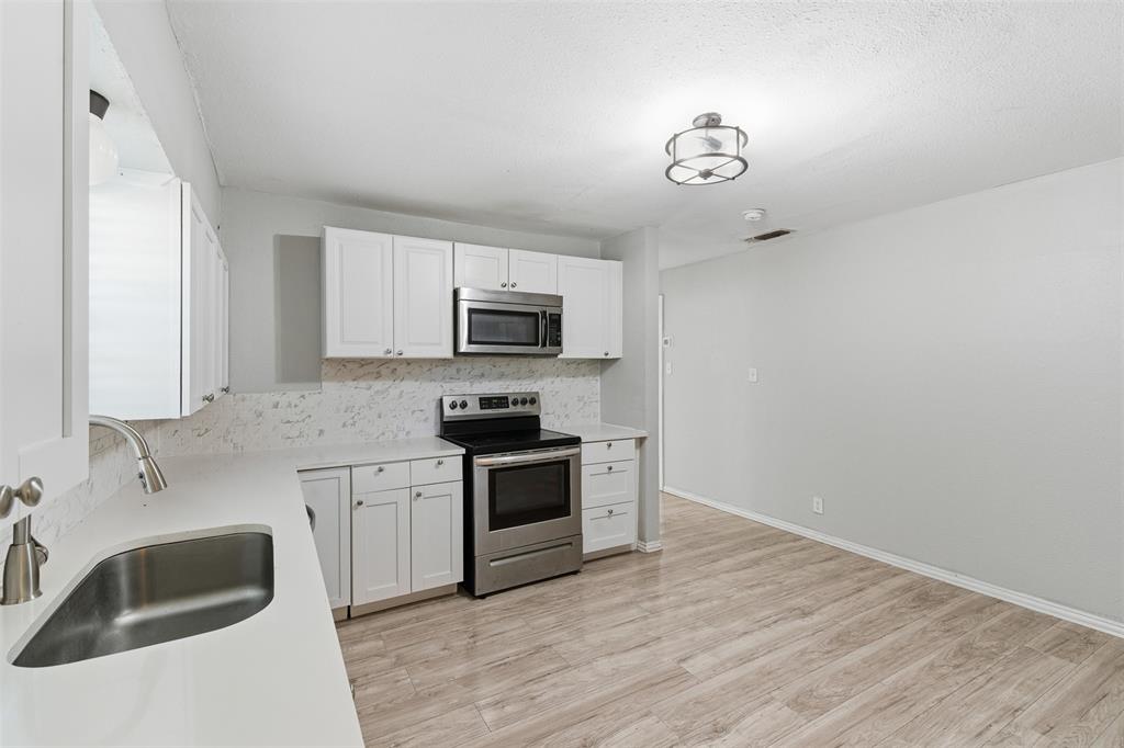 405 North Carr Avenue Sherman, TX 75090 - Photo 3 of 22 a kitchen with granite countertop a sink stainless steel appliances and white cabinets