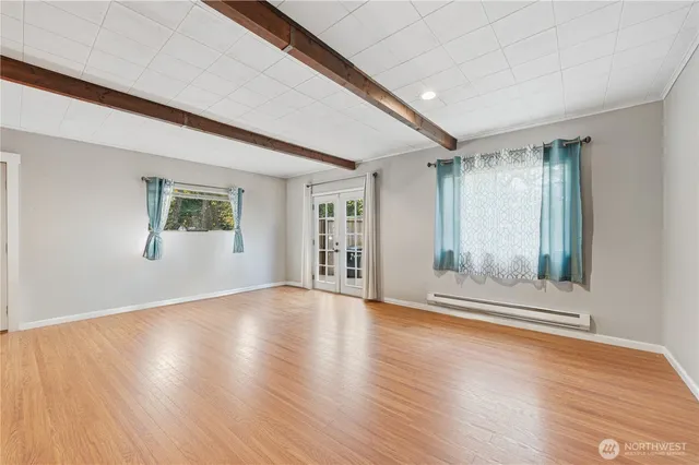a view of an empty room with wooden floor and a window
