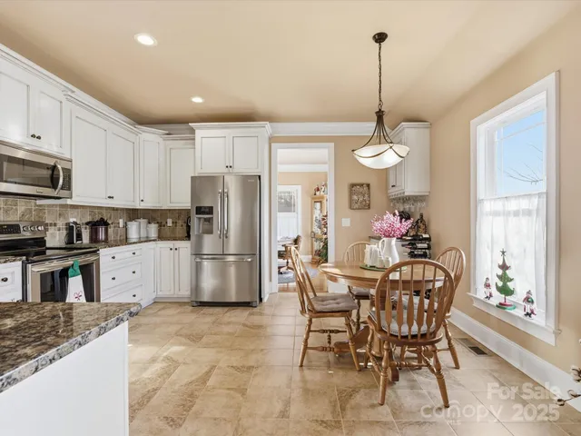 a kitchen with stainless steel appliances granite countertop a stove a refrigerator a kitchen island a dining table and chairs with wooden floor