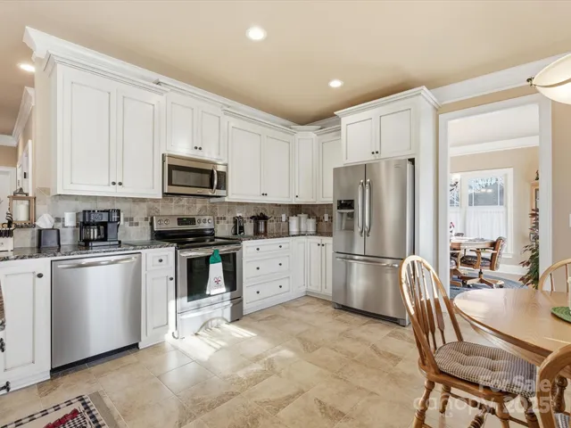 a kitchen with granite countertop a refrigerator stove top oven and sink