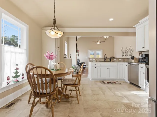 a dining room with furniture a chandelier and kitchen view