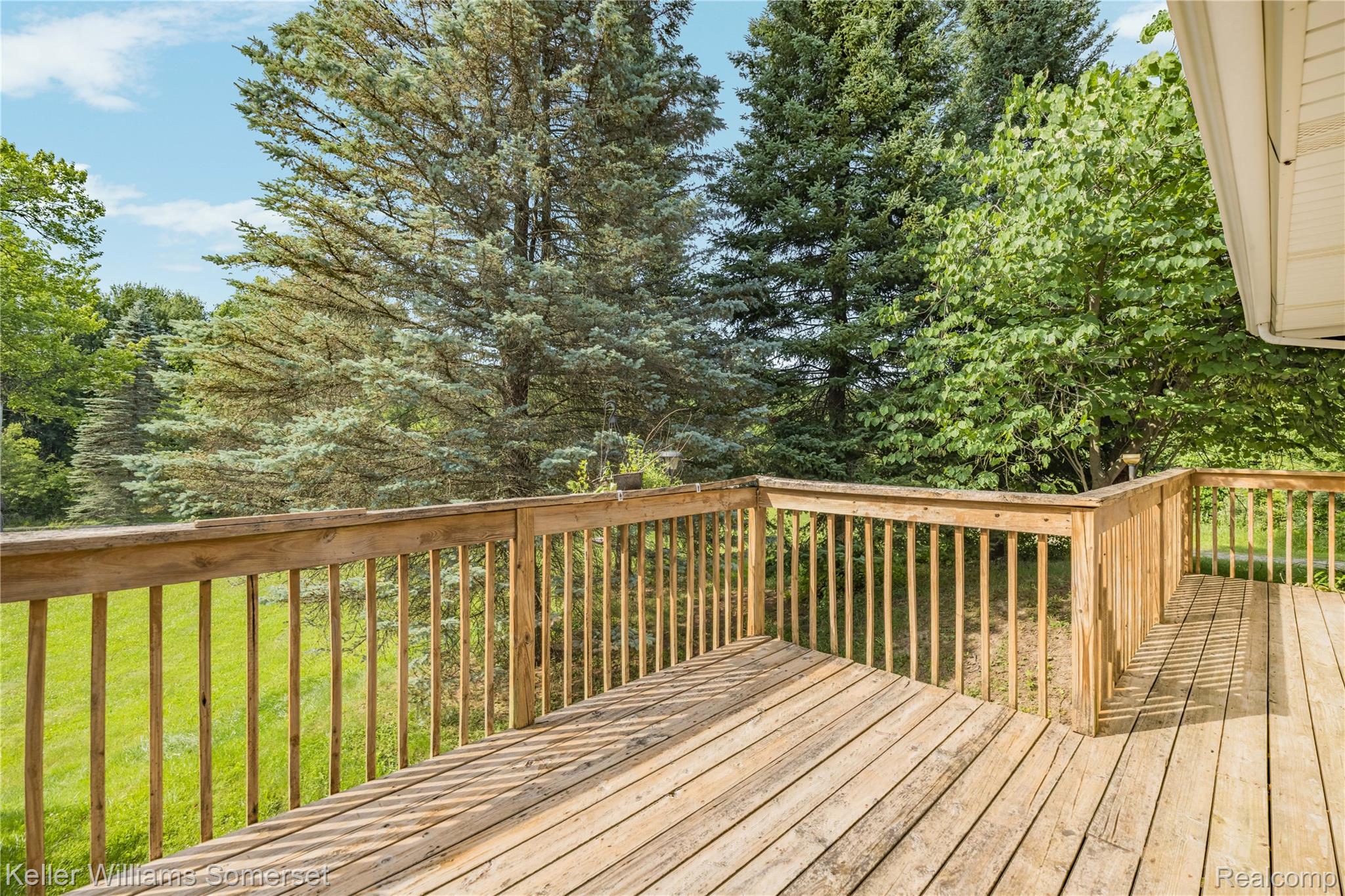 2344 Rochester Road Leonard, MI 48367 - Photo 49 of 66 Expansive wooden deck with natural wood railing, surrounded by mature trees and verdant foliage