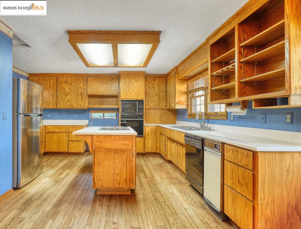19195 Ferretti Road Groveland, CA 95321 - Photo 6 of 51 Kitchen featuring open shelves, light countertops, light wood-style floors, a center island, and a textured ceiling