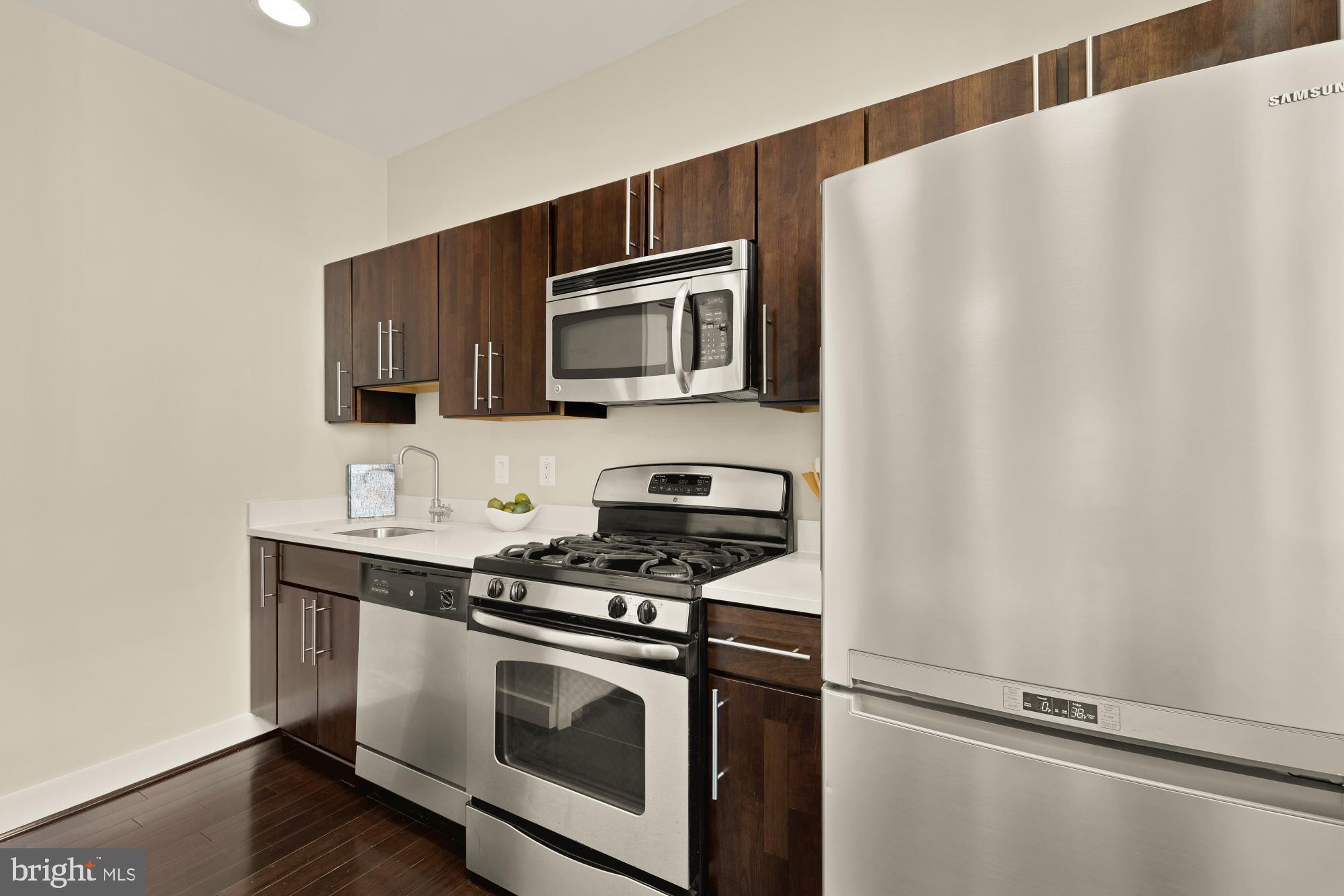 315 G Street Northeast, Unit 303 Washington, DC 20002 - Photo 6 of 16 a kitchen with granite countertop cabinets stainless steel appliances and wooden floor