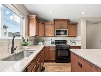 a kitchen with granite countertop a stove sink and a microwave