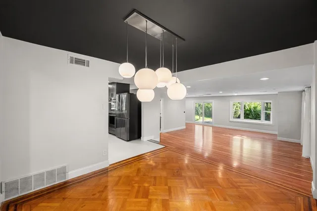 a view of a dining room with furniture a chandelier and large windows