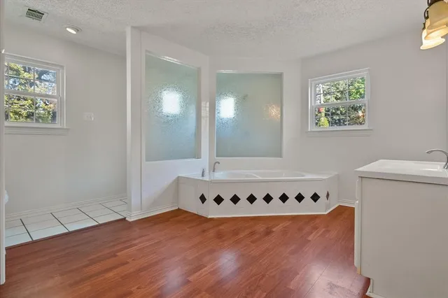 a view of an empty room with wooden floor and a ceiling fan
