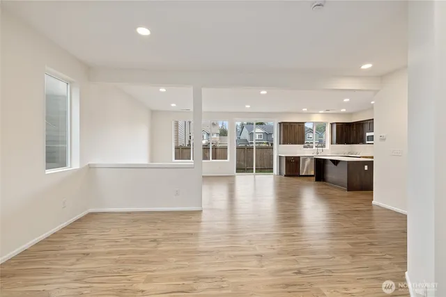 a view of a kitchen with kitchen island a sink wooden floor and a large window