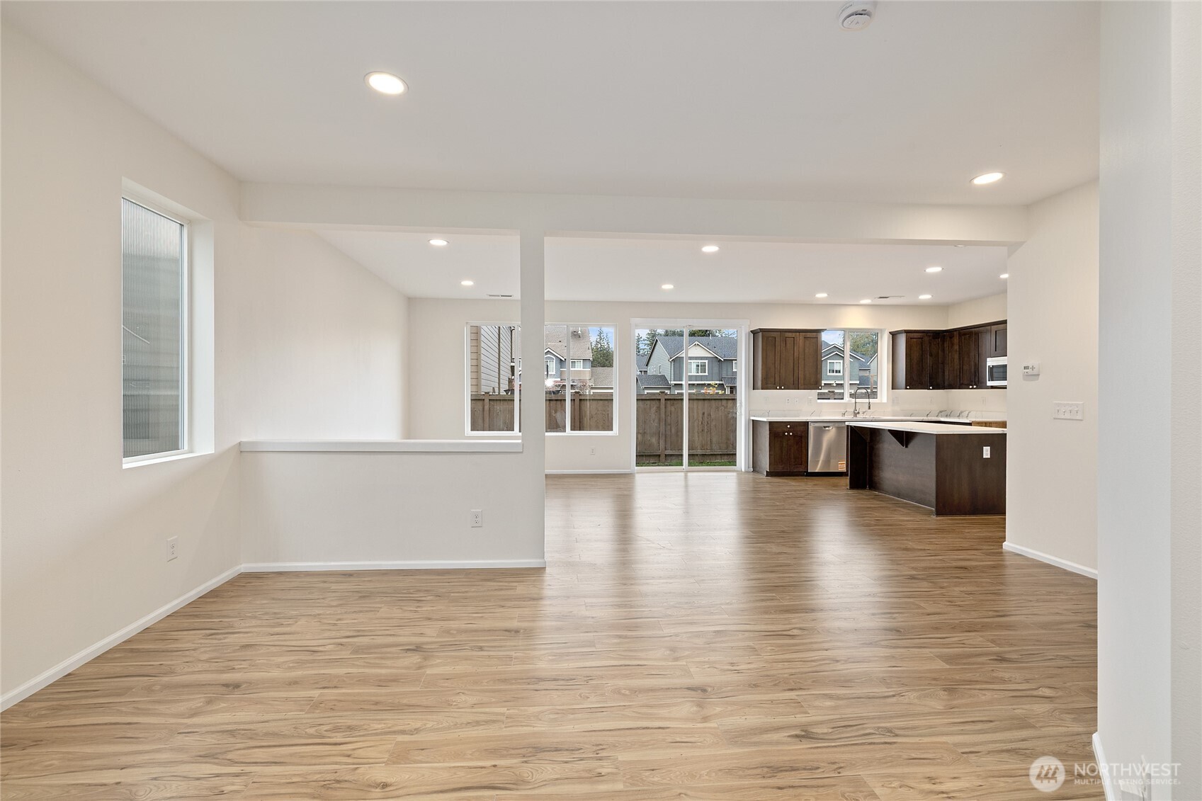 8117 175th St Court East Puyallup, WA 98375 - Photo 4 of 40 a view of a kitchen with kitchen island a sink wooden floor and a large window