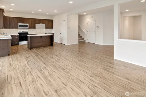 a view of kitchen with kitchen island wooden floor center island and stainless steel appliances