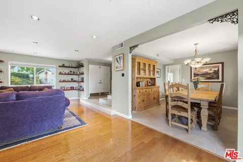 a living room with furniture wooden floor and a kitchen view