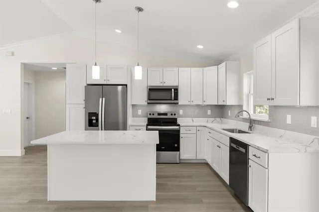 a large kitchen with stainless steel appliances granite countertop a stove a sink and a refrigerator