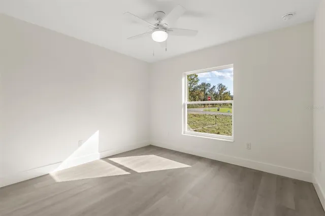 an empty room with windows and fan